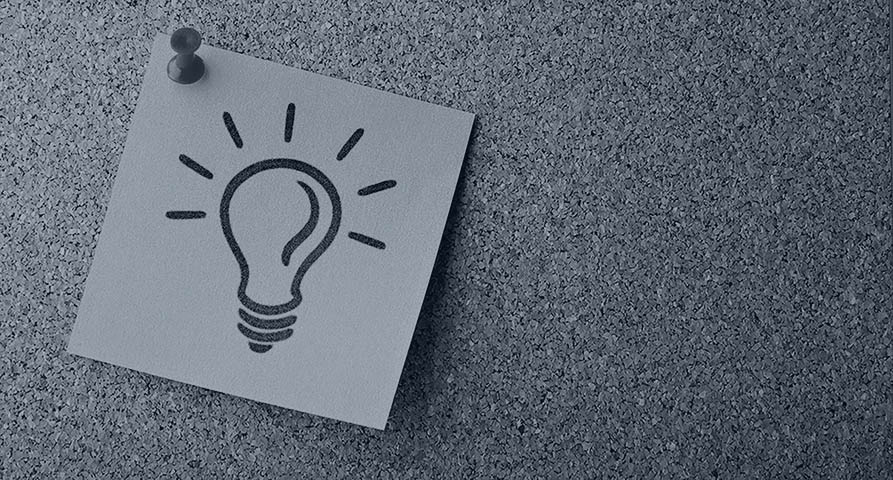 sticky note with outline of a lightbulb stuck to a cork board